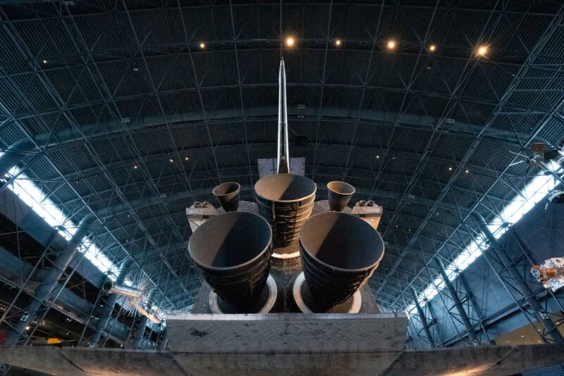 Space Shuttle Discovery's tail and engine nozzles seen from below inside the museum hangar
