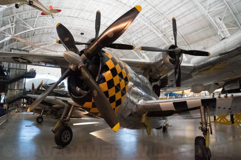 Checkered yellow and black nose art on a WWII fighter plane inside an air and space museum hangar