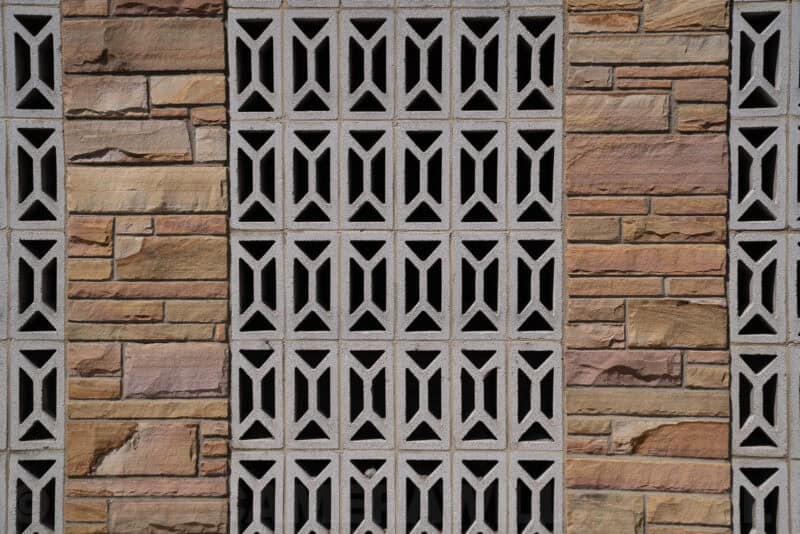 Decorative concrete breeze-block wall panel with geometric cutouts and stone tile accents