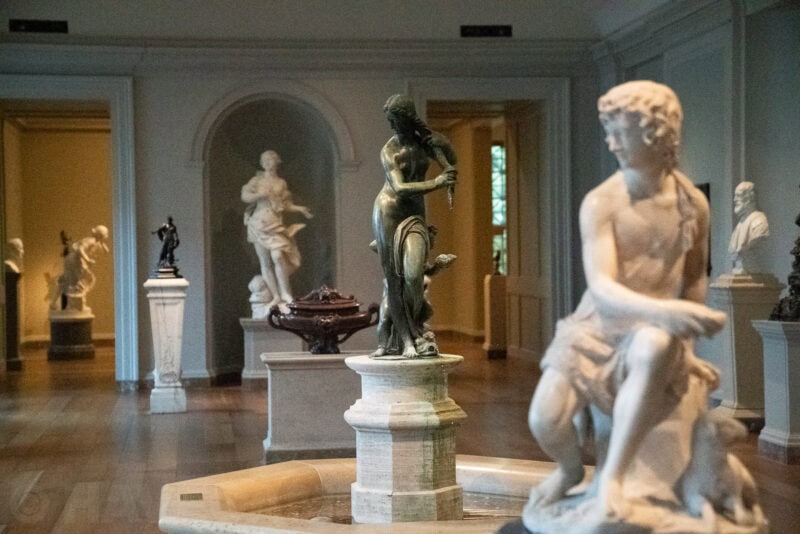 Gallery room with classical marble and bronze statues arranged around a fountain
