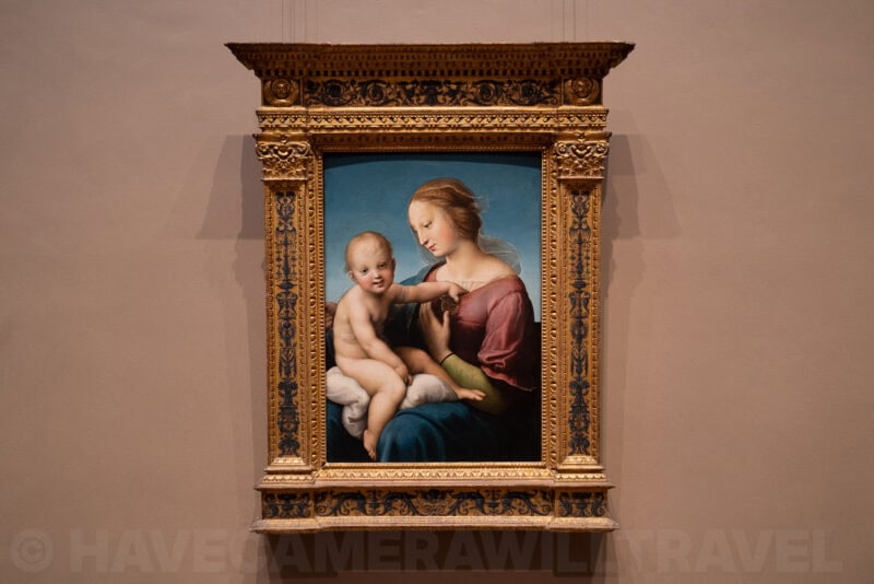 Raphael's Madonna and Child painting displayed in an ornate gilded frame on a museum wall