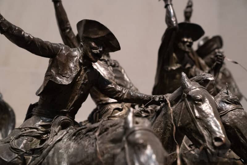 Close-up of a bronze cavalry statue showing riders on horseback with raised arms and weapons