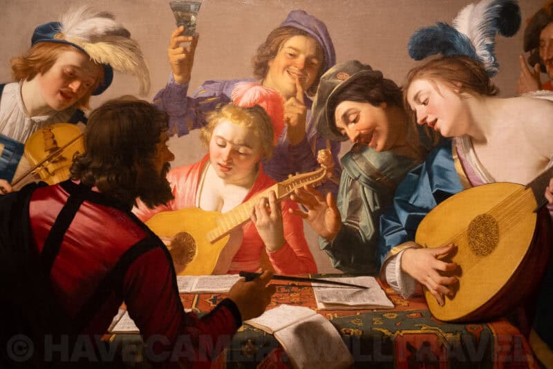 Close-up of an old oil painting showing musicians and revelers with lutes and wine