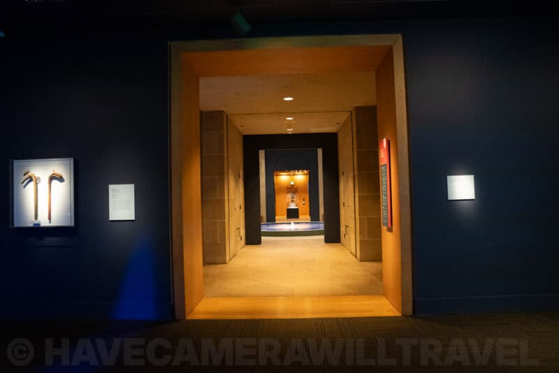 Museum hallway with a glowing archway leading through a series of doorways to a lit alcove