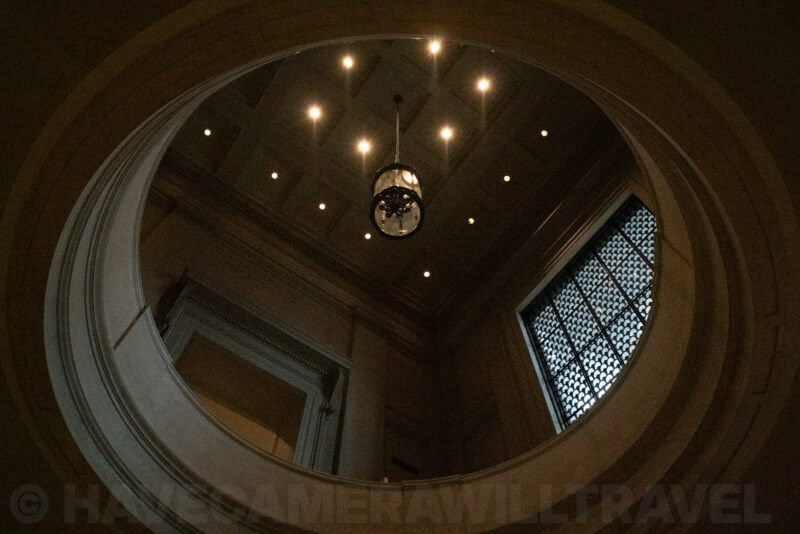 Domed skylight and arched window seen from below inside a museum rotunda with a hanging lantern