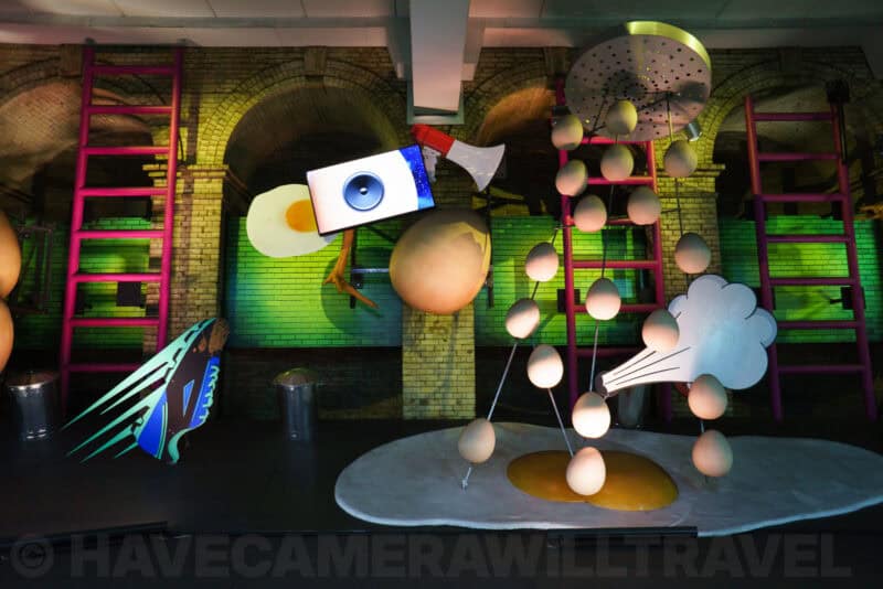 Whimsical fried-egg sculptures with dripping yolks and ladders in a surreal museum installation