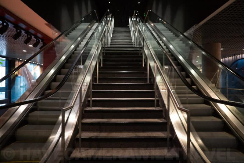 Symmetrical staircase flanked by escalators leading up inside a dark modern building
