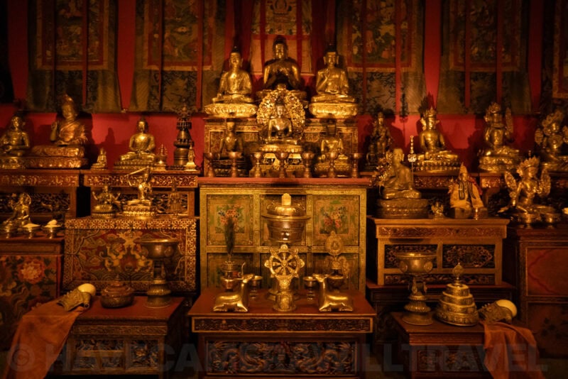 Gilded Buddhist statues and ritual objects displayed on an ornate temple altar