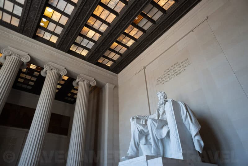 Lincoln Memorial statue viewed from below beside its Ionic columns and coffered ceiling