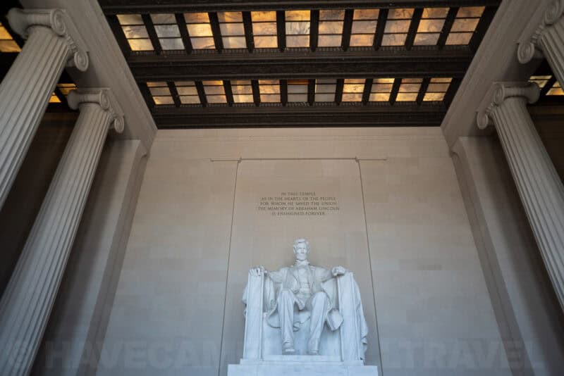 Abraham Lincoln statue inside the Lincoln Memorial, framed by ionic columns and a coffered gold ceiling