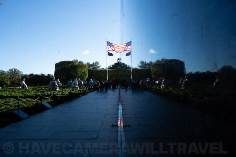 Korean War Veterans Memorial mural wall reflecting the American flag and visitors on the path