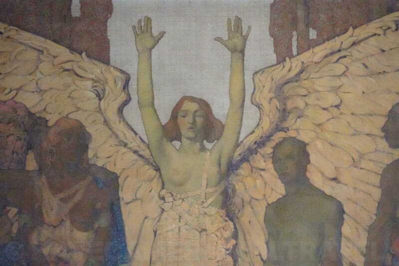 Winged angel figure with raised arms in a faded painted mural