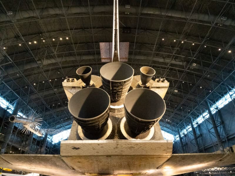 Space shuttle main engine nozzles seen from below inside a large aircraft hangar museum