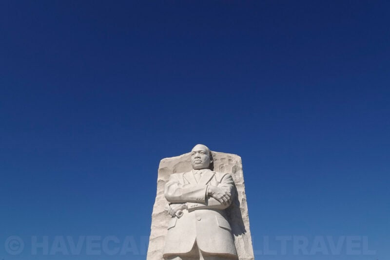 Martin Luther King Jr. Memorial statue with arms crossed against a deep blue sky
