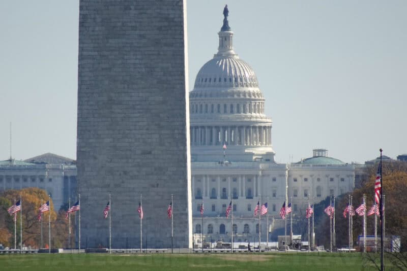 Washington Monument obelisk and US Capitol dome seen above rows of American flags
