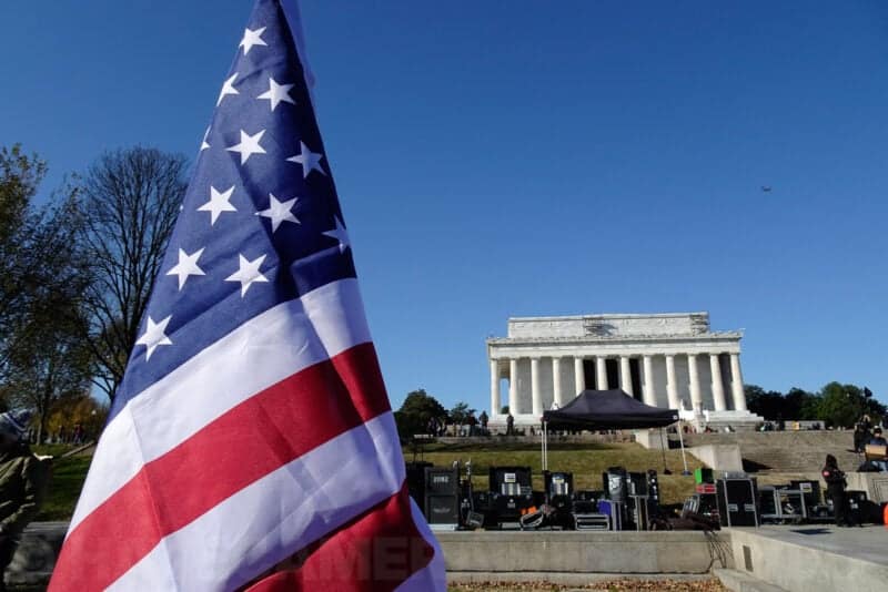 American flag in the foreground with the Lincoln Memorial and event setup in the background