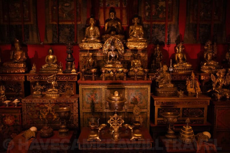 Rows of gilded Buddhist statues displayed on a shrine altar in low ambient light