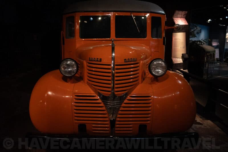 Vintage orange truck cab with round headlights displayed in a museum exhibit