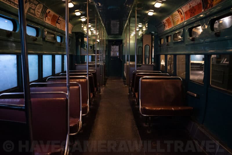 Empty vintage streetcar interior with worn leather seats and overhead advertising panels