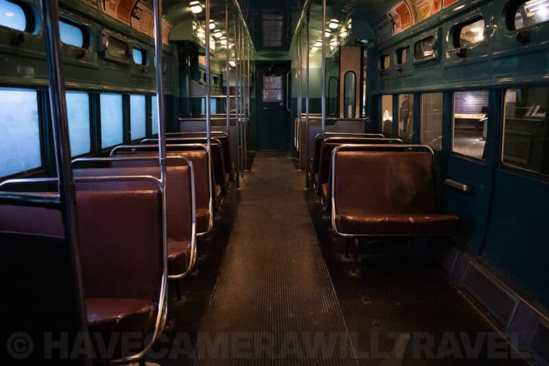 Dim vintage streetcar interior with rows of empty seats and overhead ad cards