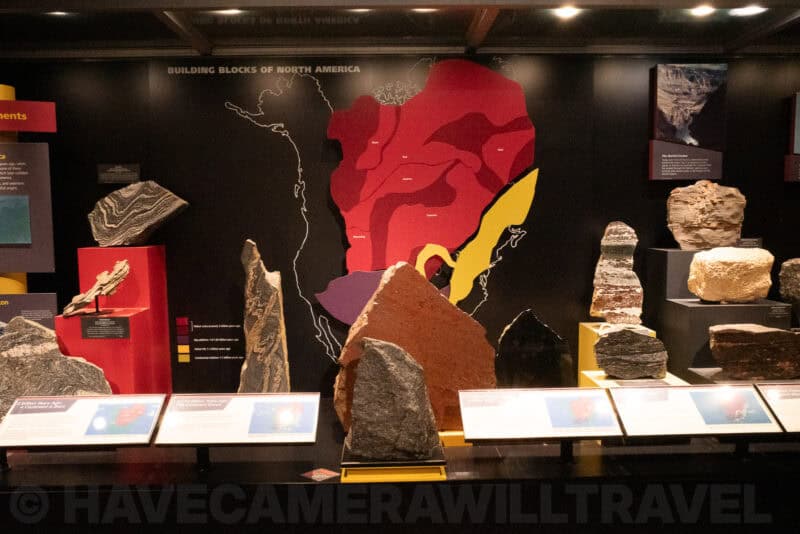 Museum geology exhibit showing rock specimens beside a North America map display