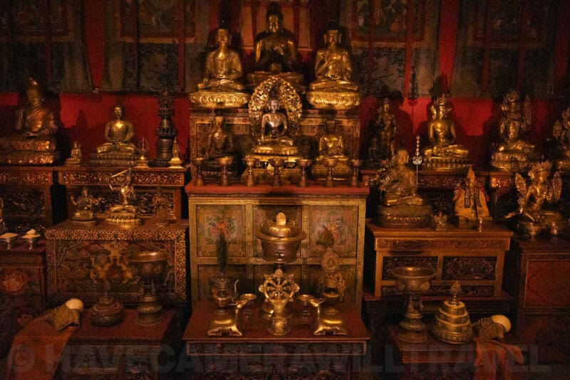 Rows of gilded Buddhist statues on a temple altar lit in warm dim light