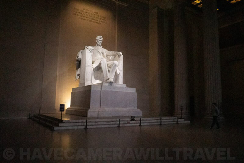 Lincoln Memorial statue illuminated at night with a visitor walking nearby
