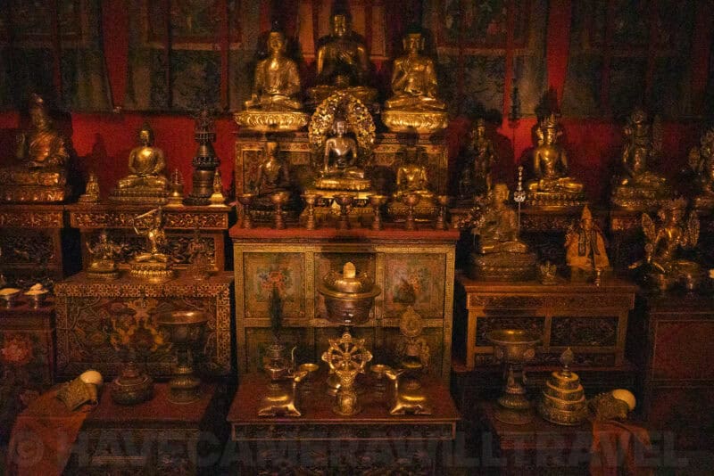 Gilded Buddhist statues displayed on an ornate temple altar in dim ambient light