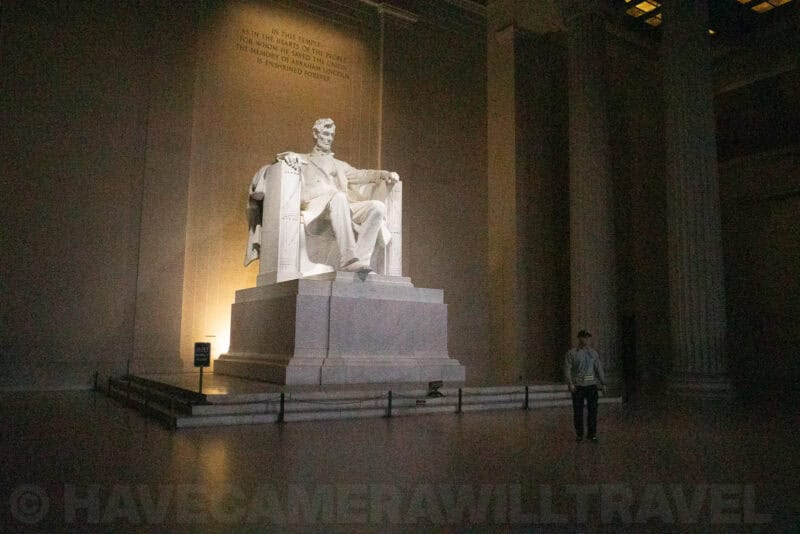 Lincoln Memorial statue lit at night with a visitor walking past the columns