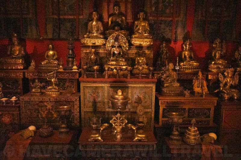 Gilded Buddhist statues arranged on a temple altar glowing in dim red light