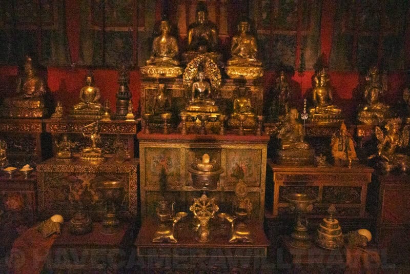 Gilded Buddhist altar statues glowing softly in a dim red-lit temple room
