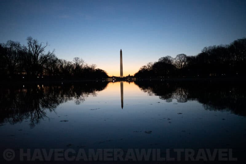 Washington Monument silhouetted at dawn with its reflection in the still Reflecting Pool