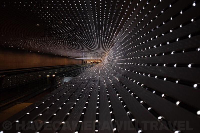 Tunnel-like corridor with rows of illuminated pinpoint lights converging in perspective