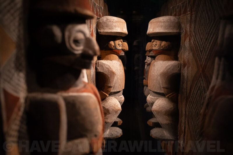 Carved wooden figures displayed in a dimly lit museum exhibit