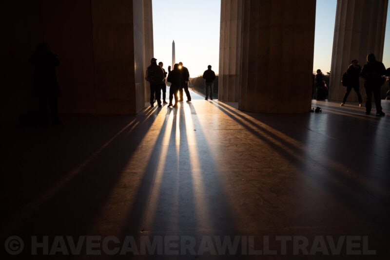 Silhouetted visitors and long shadows inside the Lincoln Memorial at sunrise
