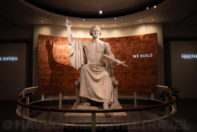 Large seated George Washington statue display inside a museum exhibit hall