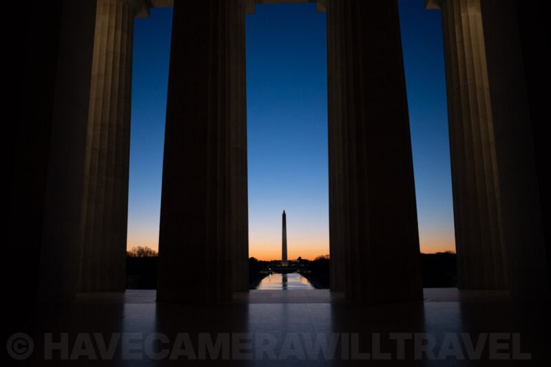 Washington Monument silhouetted at dusk framed by Lincoln Memorial columns