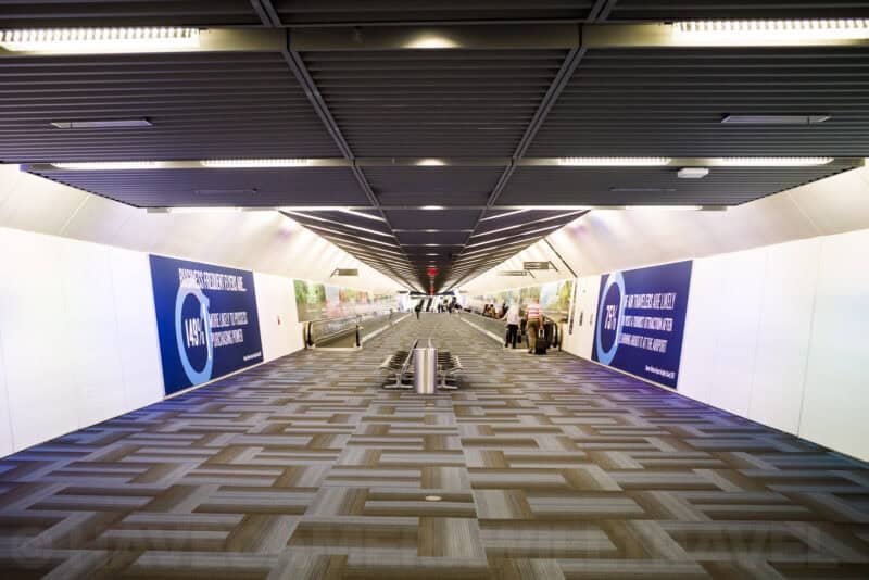 Long airport terminal corridor with moving walkways and illuminated signage