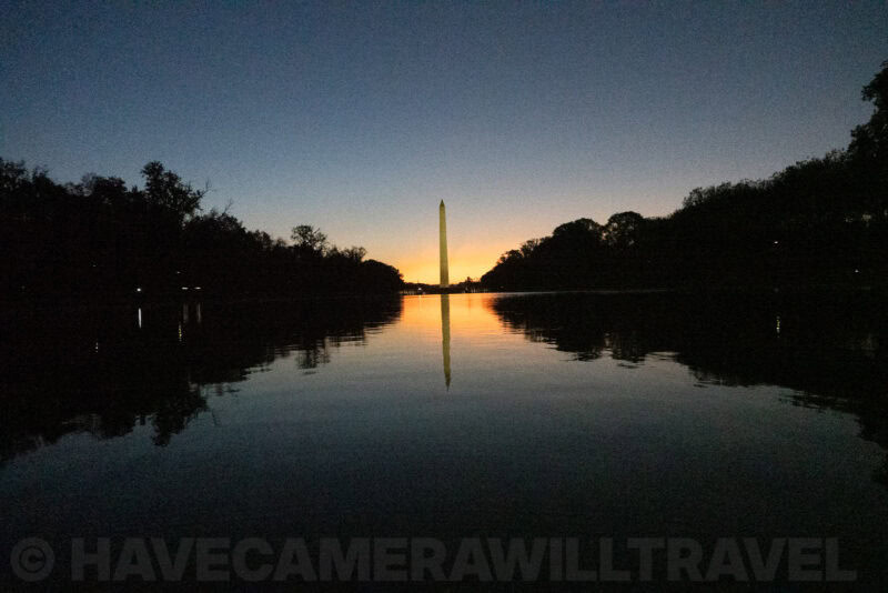Washington Monument glowing at twilight with a mirrored reflection in the Reflecting Pool