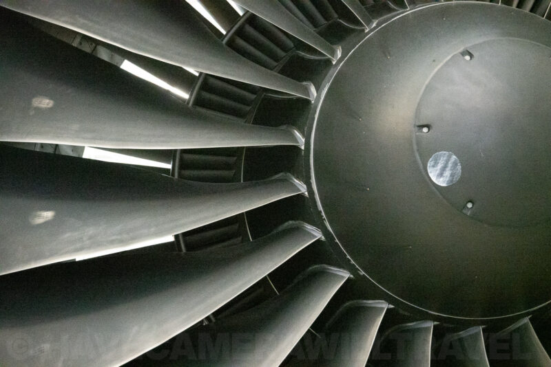Close-up view of a jet engine's fan blades and hub in low museum lighting