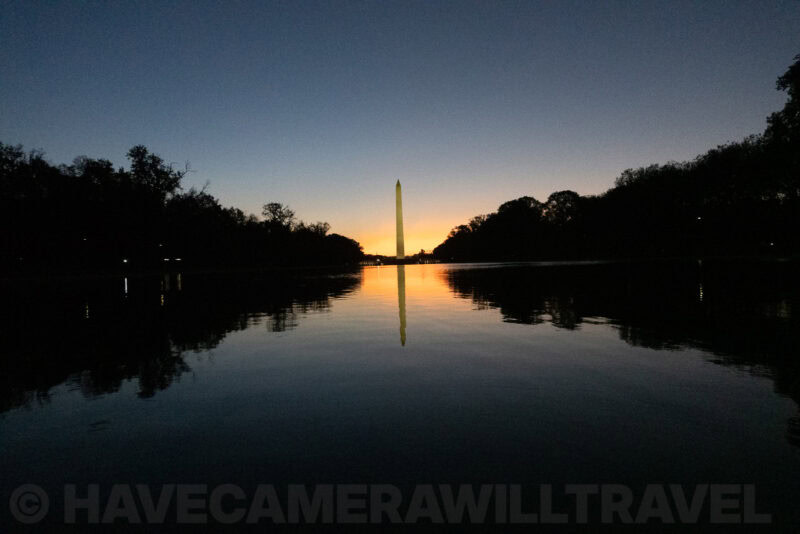 Washington Monument mirrored in the Reflecting Pool at twilight with silhouetted trees