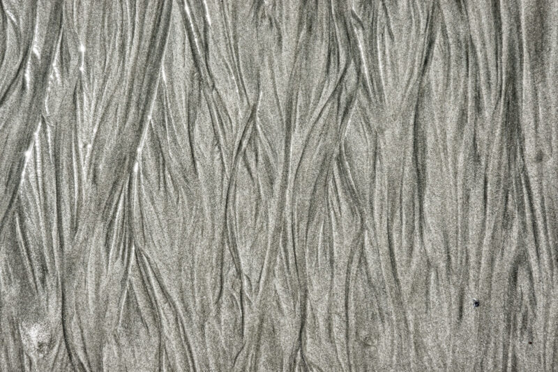 Textured wet sand patterns on a beach in monochrome tones