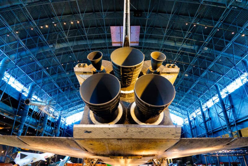 Space shuttle's rear engine nozzles viewed from below inside a museum hangar