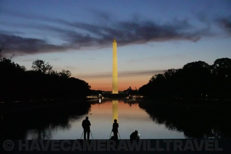 Washington Monument glowing at dusk reflected in the Lincoln Memorial Reflecting Pool with photographers on tripods