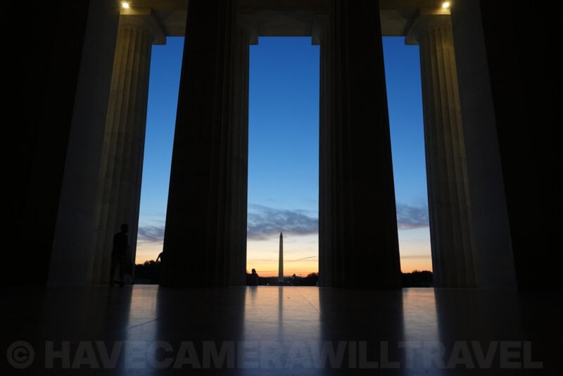 Washington Monument silhouetted between the columns of the Lincoln Memorial at dusk
