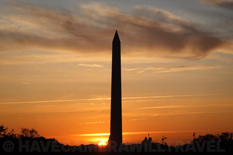 Washington Monument silhouetted against a fiery orange sunset sky