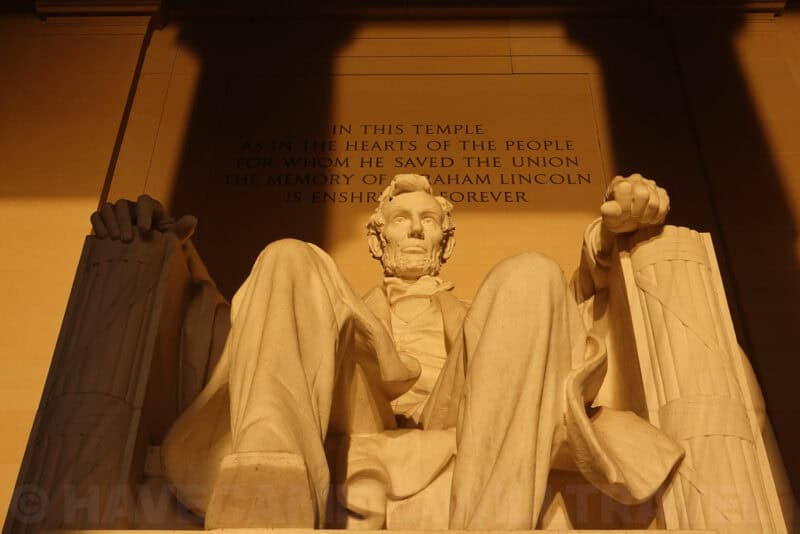 Lincoln Memorial statue and inscribed wall lit in warm evening light, seen from below