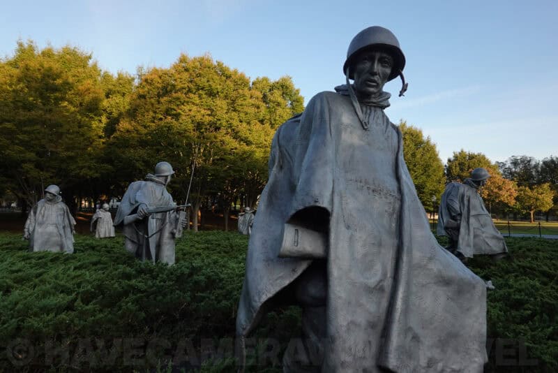 Bronze soldier statues in ponchos among bushes at the Korean War Veterans Memorial