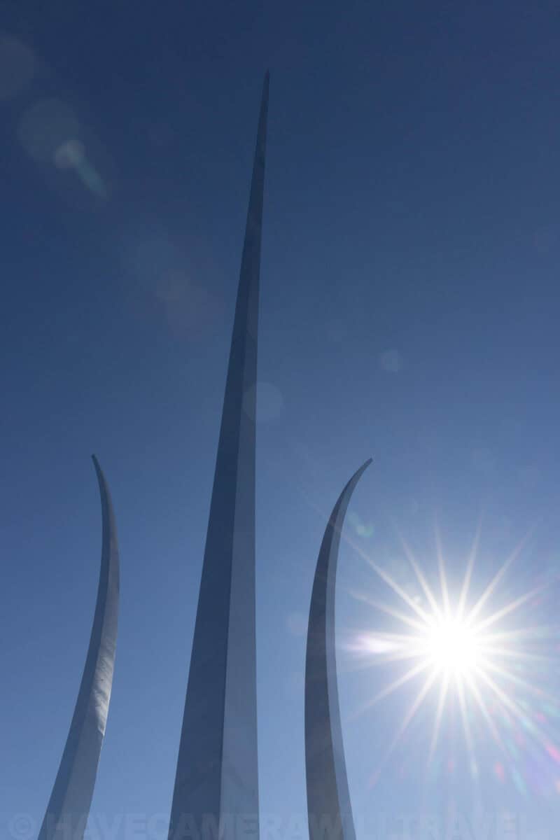 Air Force Memorial's three curved stainless steel spires rising into a blue sky with sun flare