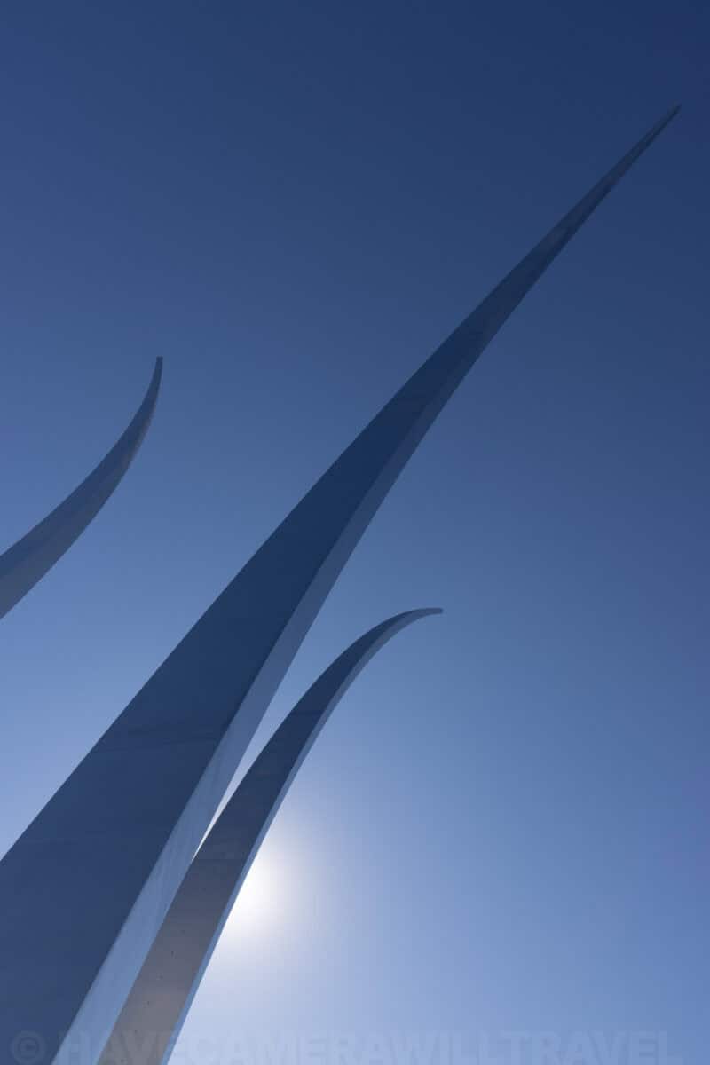 Close-up of the Air Force Memorial's steel spires backlit by the sun in a blue sky